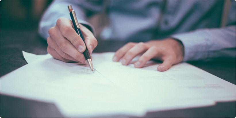 Man writing on stacks of paper.